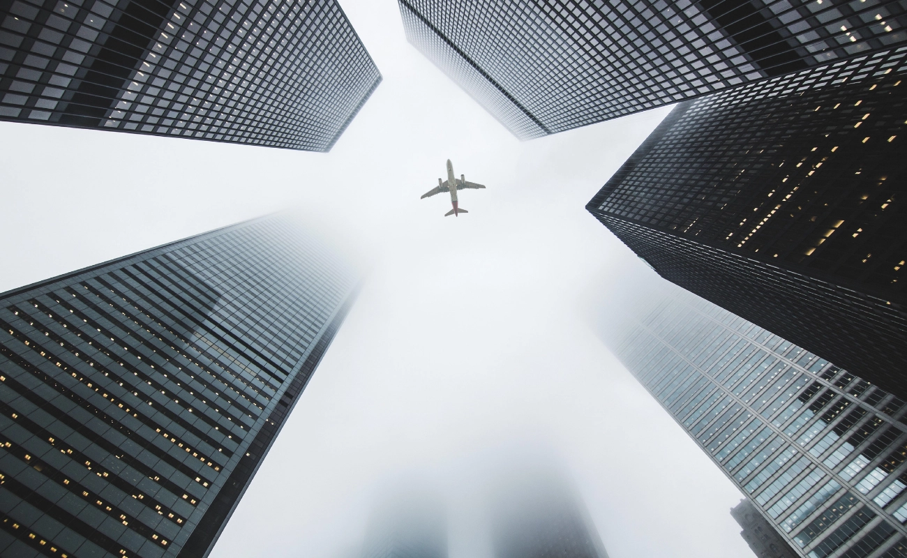 Global Immigration Consultants in Dubai – Your Gateway to New Opportunities Airplane flying above skyscrapers representing global travel and immigration consultants in Dubai